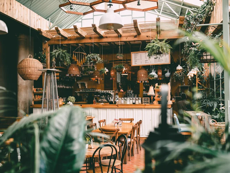 植物に囲まれた温かみのあるカフェの店内空間